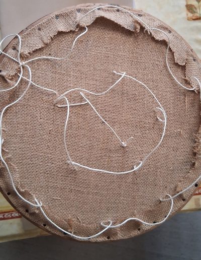 Lacets avant mise en crin sur tabouret de piano rond.