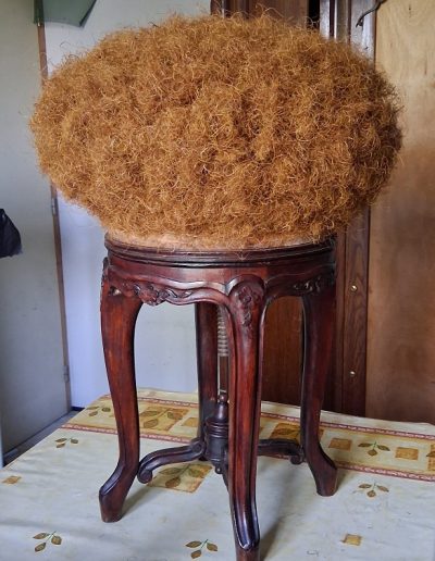 Etape de la restauration de sièges : Mise en crin d’un tabouret de piano rond.